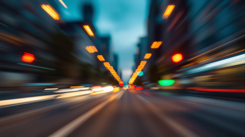 Stadtstraße bei Dämmerung mit fließendem Verkehr und Ampeln