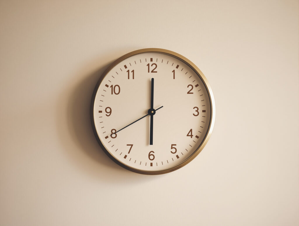 Analoge Wanduhr als Symbol für Wartezeit und verzögerten Wirkungseintritt
