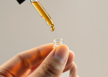 Cannabis-Extrakt-Tropfen an Pipette vor neutralem Hintergrund