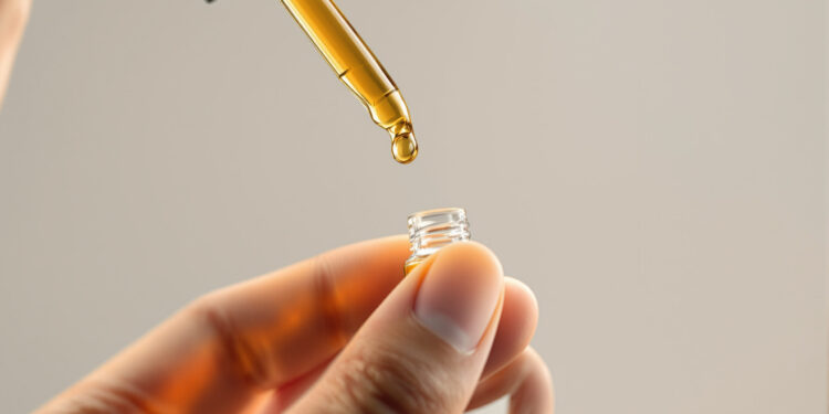 Cannabis-Extrakt-Tropfen an Pipette vor neutralem Hintergrund