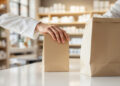 Apothekentheke mit Hand beim Verpacken eines Produkts in neutraler Papiertüte