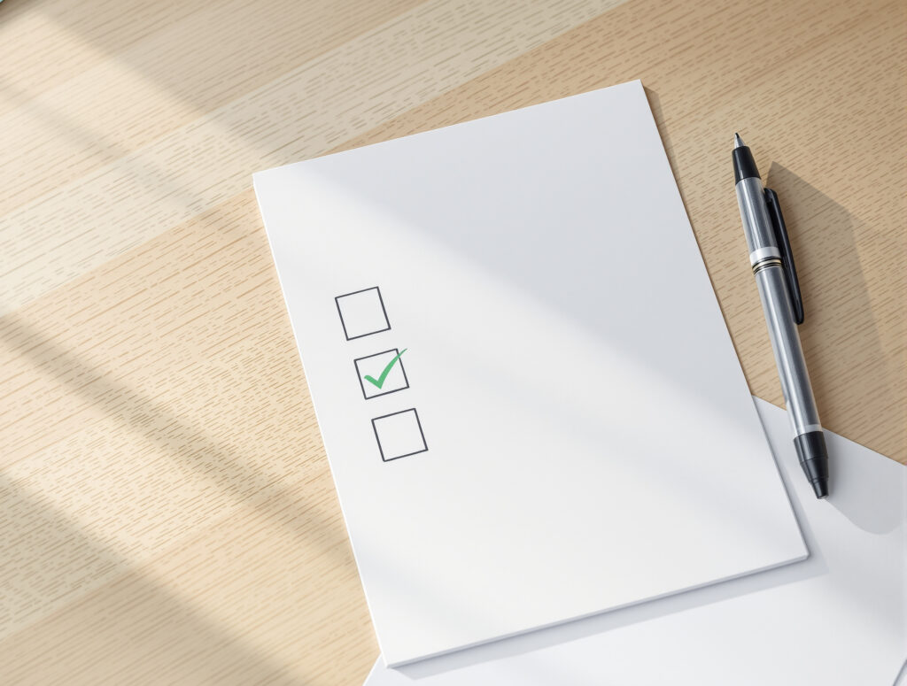 Checkliste mit Stift auf Tisch, Kontrollkästchen teils abgehakt