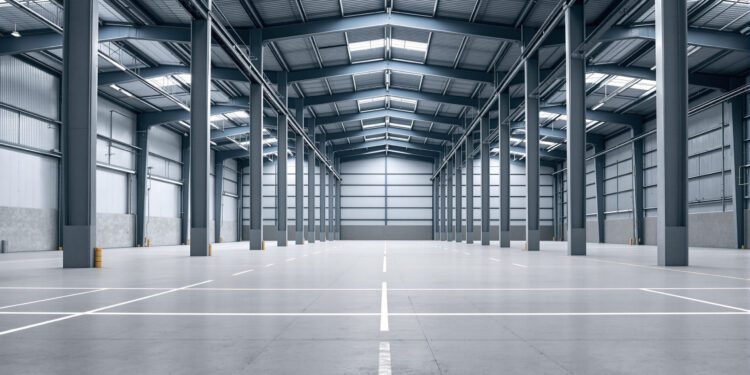 Leere Industriehalle mit Betonboden und Stahlträgern