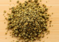 Gemahlenes Cannabis in mittlerer Konsistenz auf Holzfläche